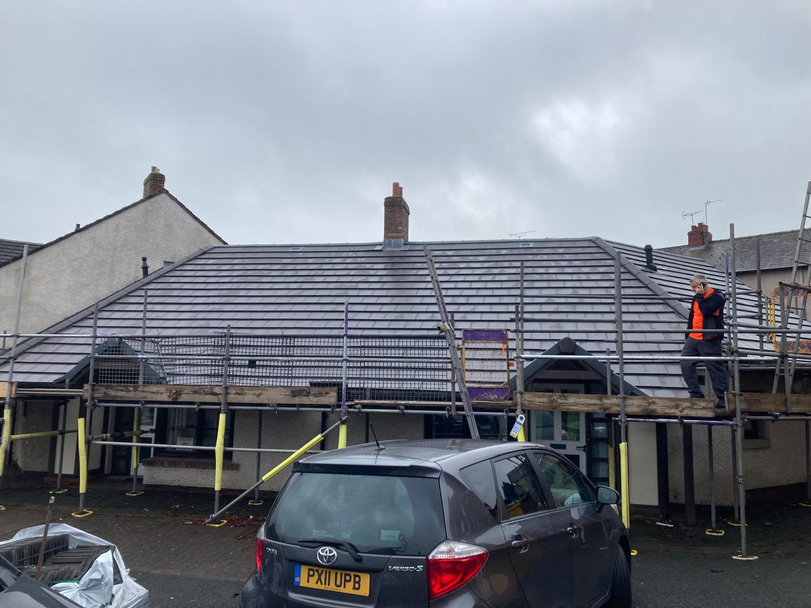 Bungalow with new grey tiled roof and full scaffolding