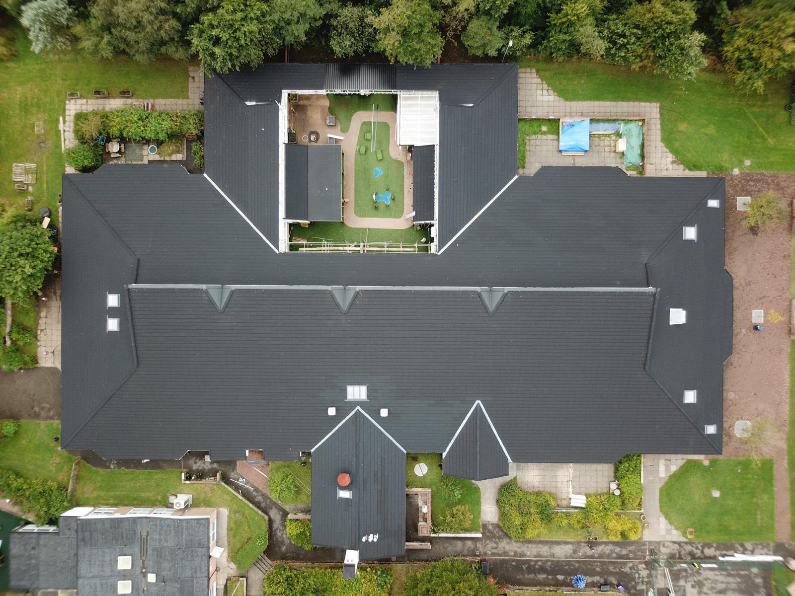 Aerial view of a large dark tiled roof with central courtyard