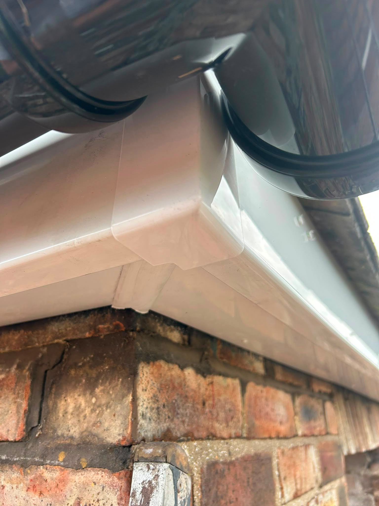 White fascia and black guttering at a brick corner