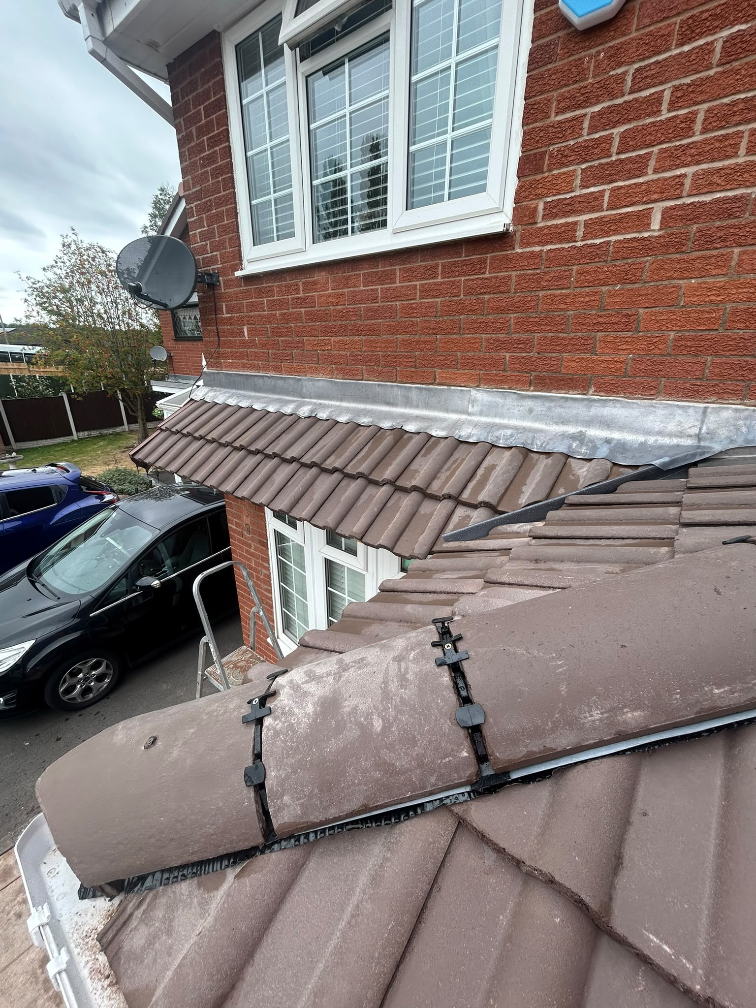 Lead flashing and dry ridge tiles on a brown tiled roof