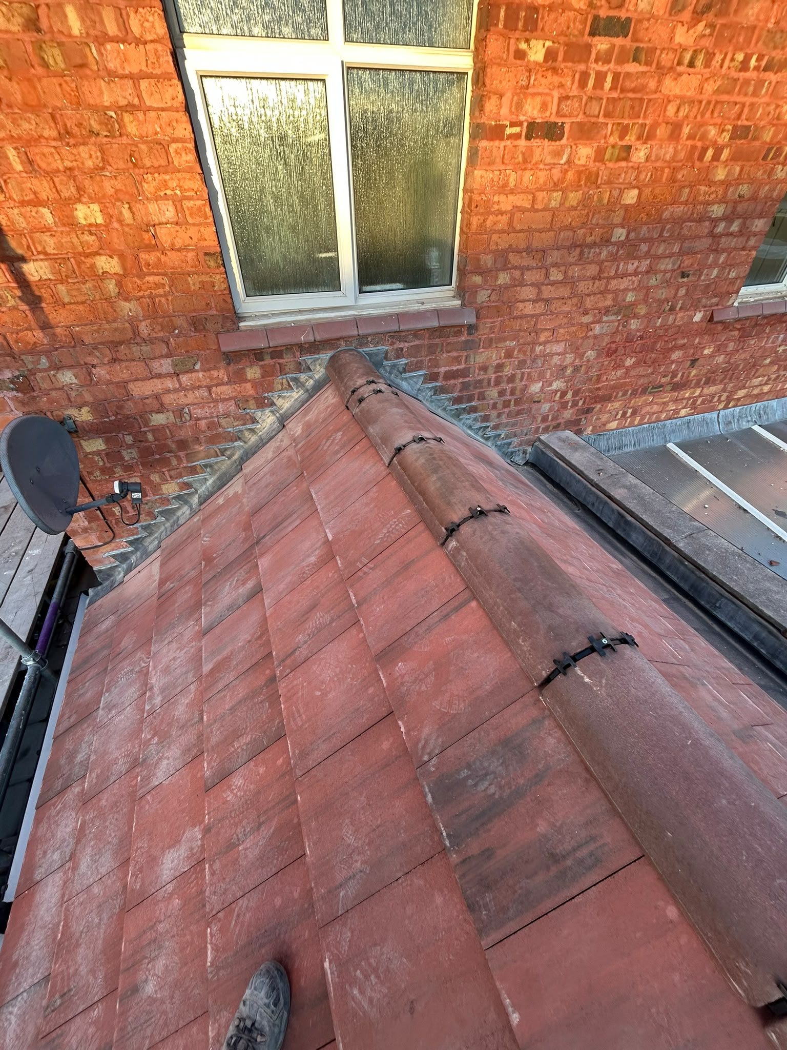 Stepped lead flashing and dry ridge tiles at a brick abutment
